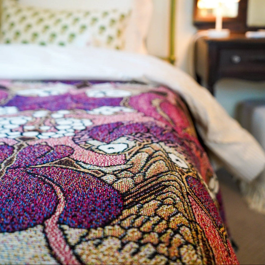 Bed with a colorful patterned blanket in a bedroom setting.