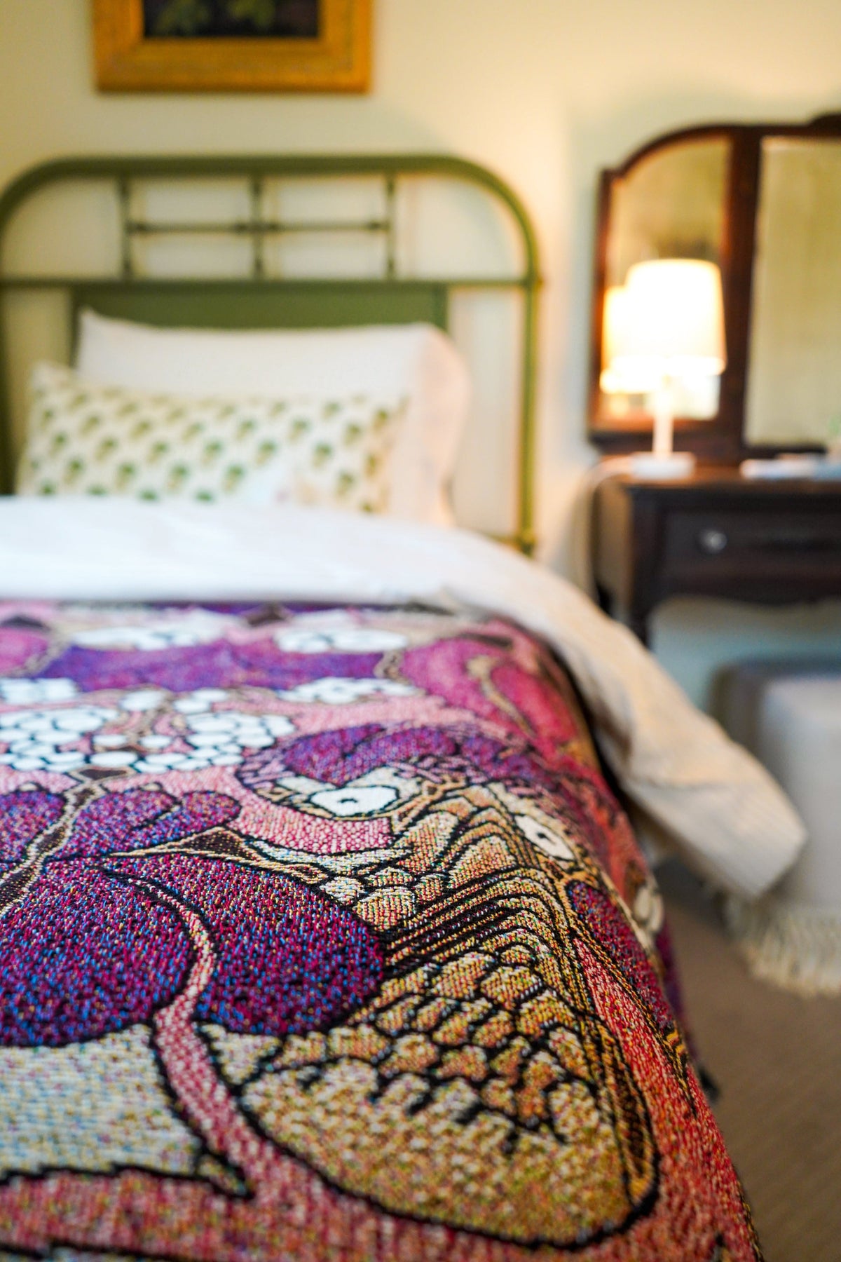 Bed with a colorful patterned blanket in a bedroom setting.